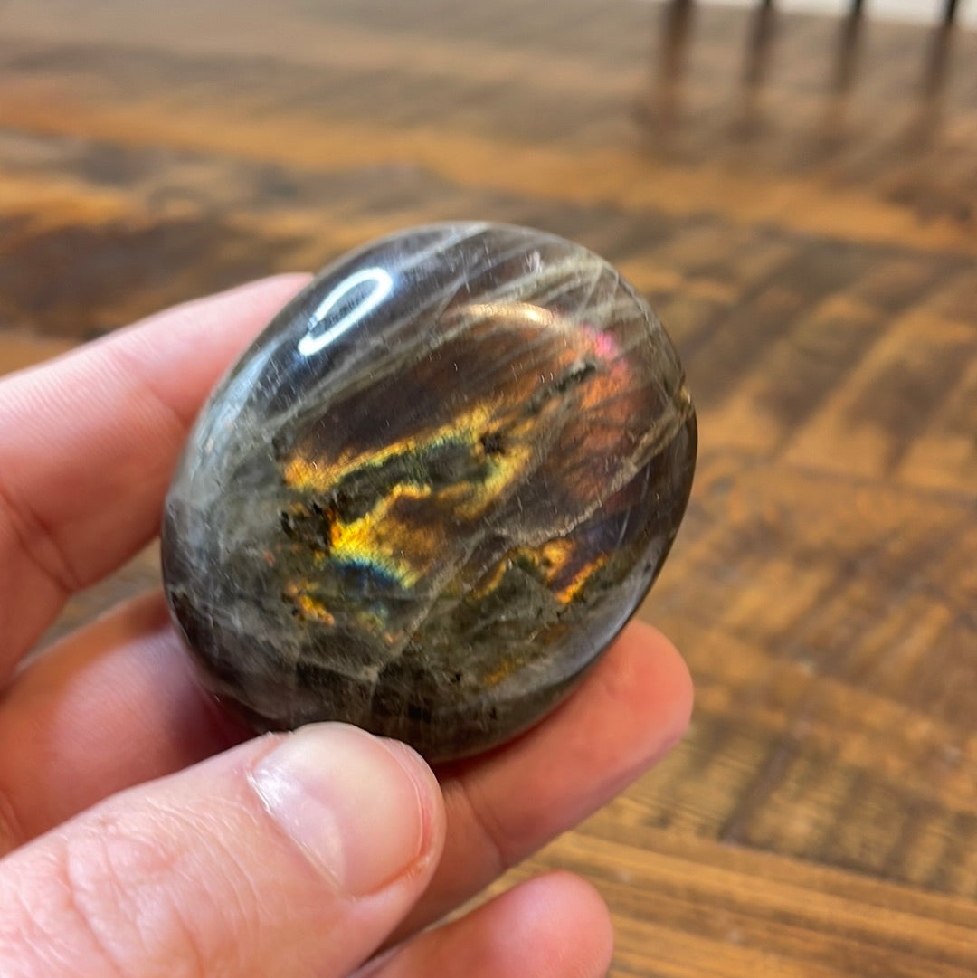 Labradorite palm stones featuring a captivating spectrum of pink, purple, green, gold and orange hues, enhanced by rainbow flashes for a unique vibrant crystal experience.
