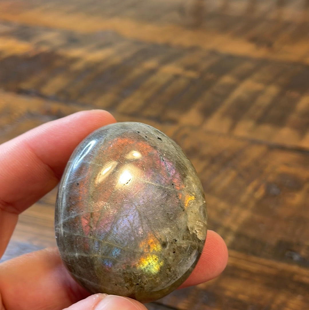 Labradorite palm stones featuring a captivating spectrum of pink, purple, green, gold and orange hues, enhanced by rainbow flashes for a unique vibrant crystal experience.