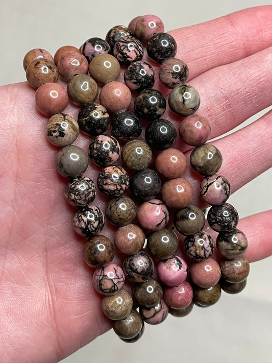 Rhodonite bracelet with 8mm beads, showcasing the harmonious blend of pink and black hues in the rhodonite gemstone. This bracelet exudes a sense balance and elegance, making it a charming accessory for various occasions.