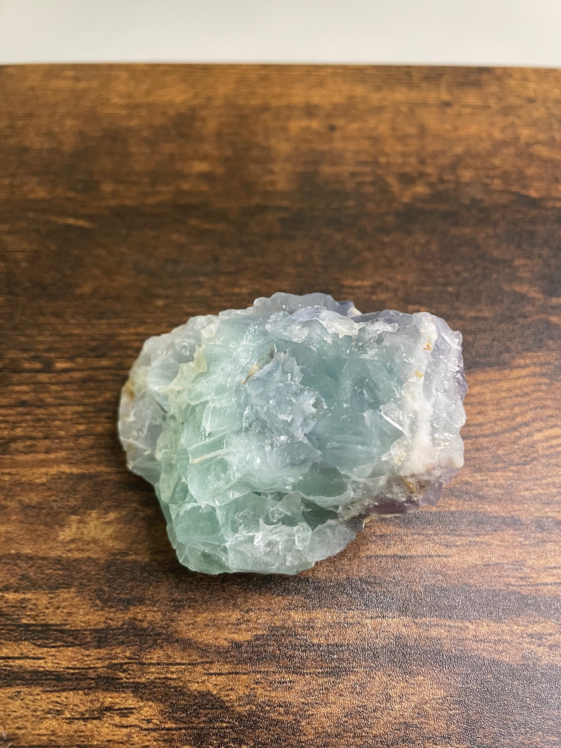 A raw Fluorite crystal in it's natural state, featuring a mix of translucent green and purple hues, reflecting the captivating beauty of this mineral's unique formations.