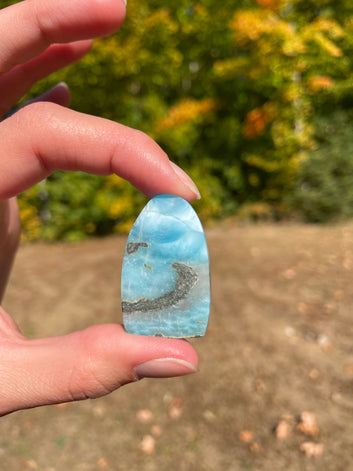 Super blue with soft white lines, oval top and flat bottom in shape with polished surface. It has effects on four of the seven Chakras