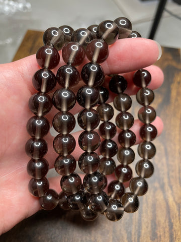 Smokey Quartz bracelet with 10mm beads, showcasing the rich, smokey brown tones of Quartz crystals, radiating a sense of grounding and sophistication in this versatile and stylish accessory.