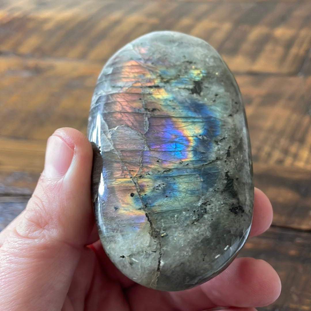 Labradorite palm stones featuring a captivating spectrum of pink, purple, green, gold and orange hues, enhanced by rainbow flashes for a unique vibrant crystal experience. 