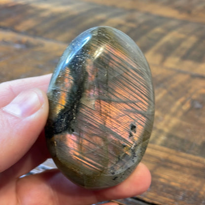 Labradorite palm stones featuring a captivating spectrum of pink, purple, green, gold and orange hues, enhanced by rainbow flashes for a unique vibrant crystal experience. 