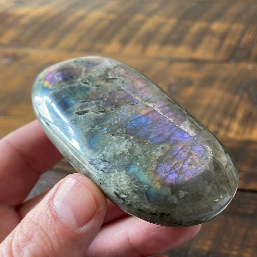 Labradorite palm stones featuring a captivating spectrum of pink, purple, green, gold and orange hues, enhanced by rainbow flashes for a unique vibrant crystal experience. 
