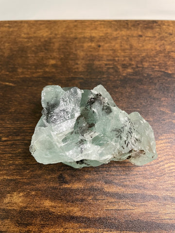 A raw Fluorite crystal in it's natural state, featuring a mix of translucent green and purple hues, reflecting the captivating beauty of this mineral's unique formations.