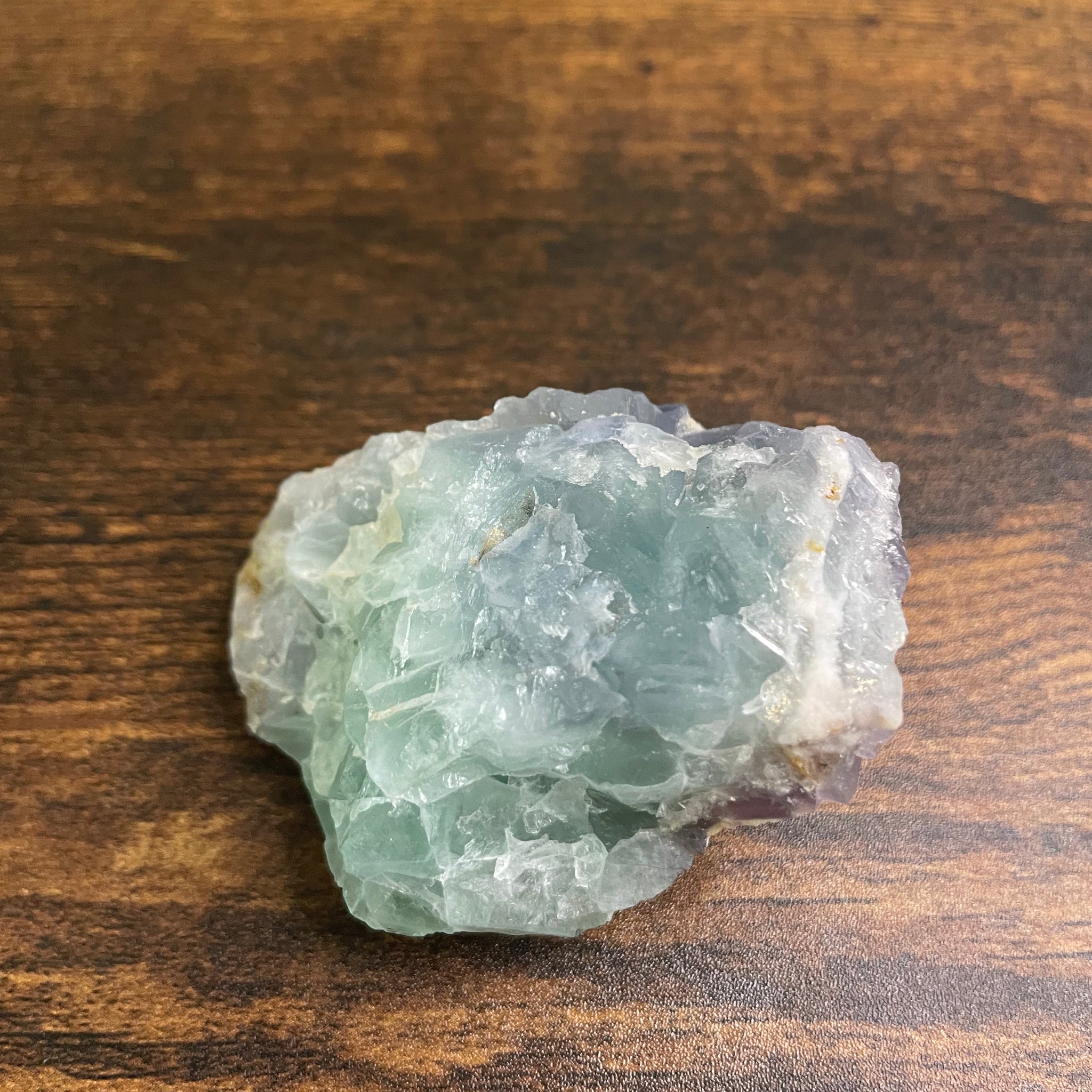 A raw Fluorite crystal in it's natural state, featuring a mix of translucent green and purple hues, reflecting the captivating beauty of this mineral's unique formations.