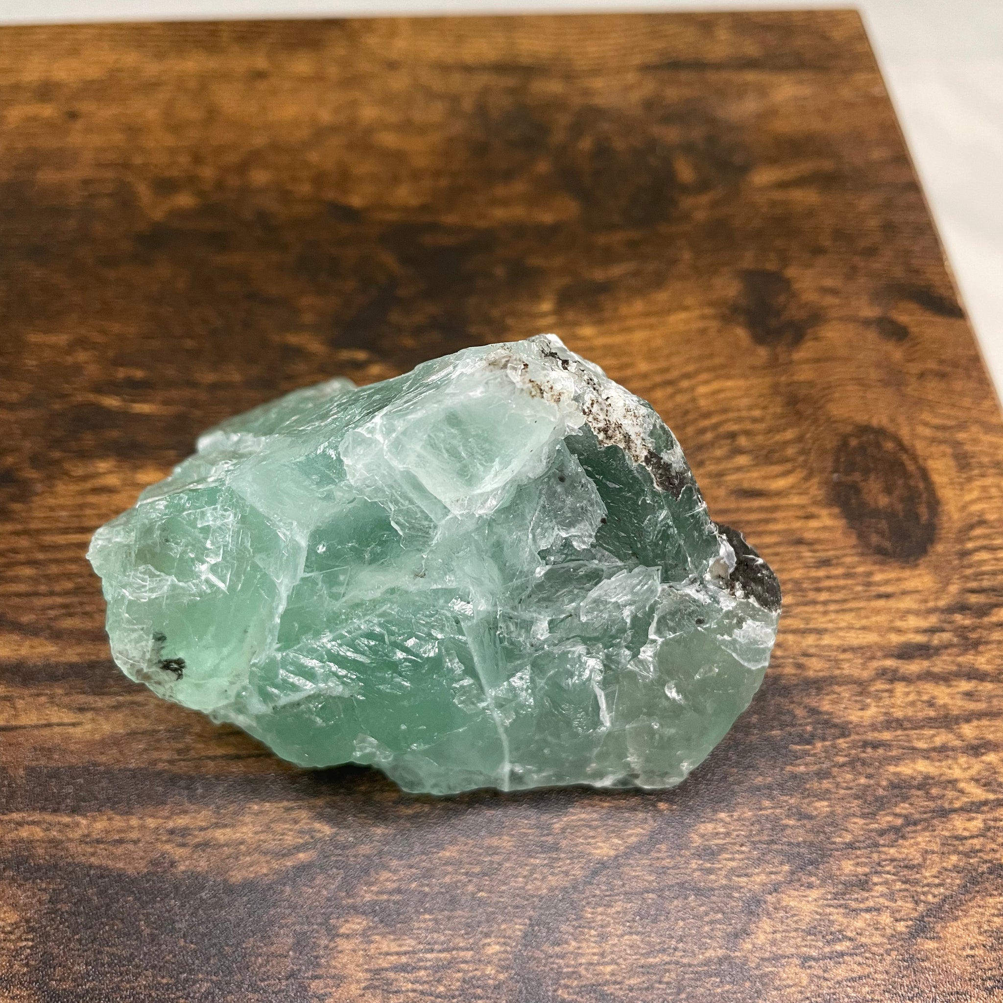 A raw Fluorite crystal in it's natural state, featuring a mix of translucent green and purple hues, reflecting the captivating beauty of this mineral's unique formations.
