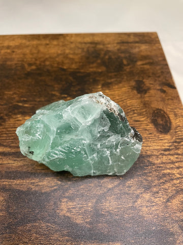 A raw Fluorite crystal in it's natural state, featuring a mix of translucent green and purple hues, reflecting the captivating beauty of this mineral's unique formations.