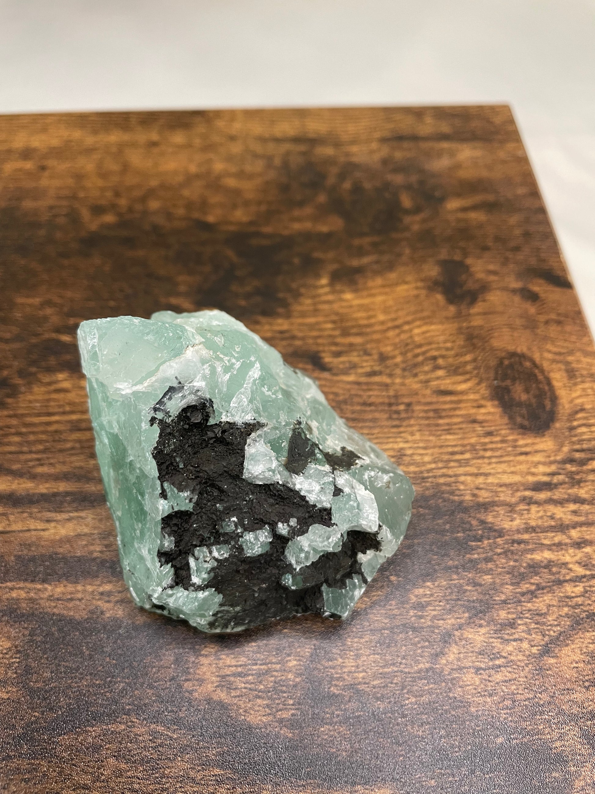 A raw Fluorite crystal in it's natural state, featuring a mix of translucent green and purple hues, reflecting the captivating beauty of this mineral's unique formations.