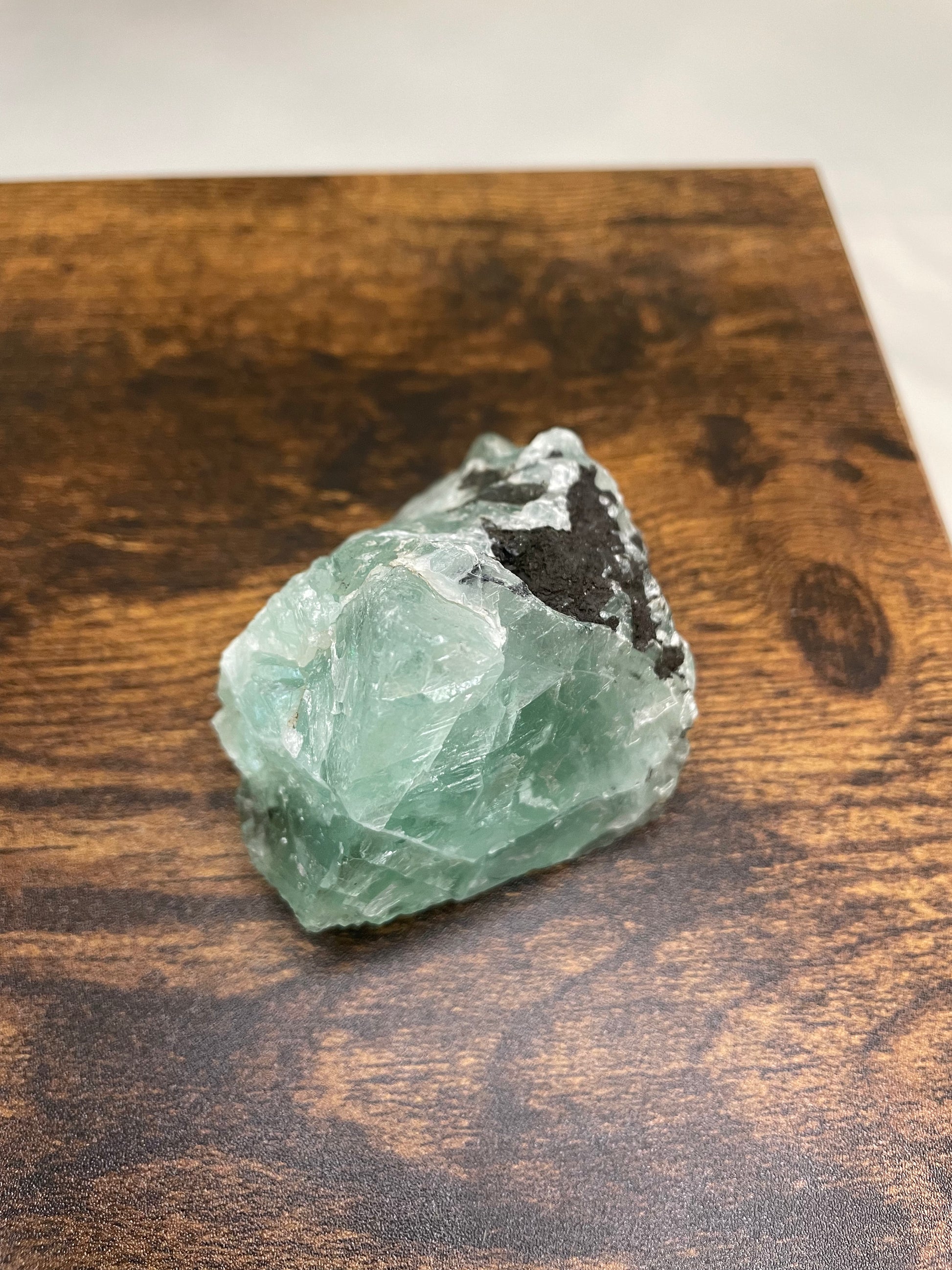 A raw Fluorite crystal in it's natural state, featuring a mix of translucent green and purple hues, reflecting the captivating beauty of this mineral's unique formations.