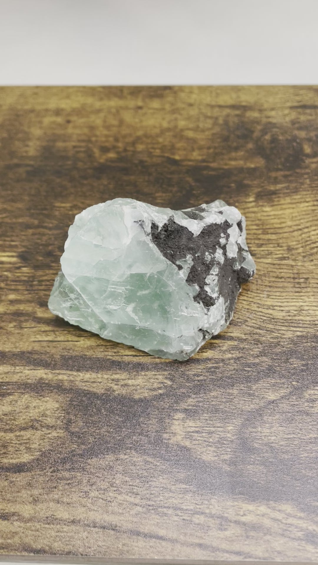 In this video, A raw Fluorite crystal in it's natural state, featuring a mix of translucent green and purple hues, reflecting the captivating beauty of this mineral's unique formations.